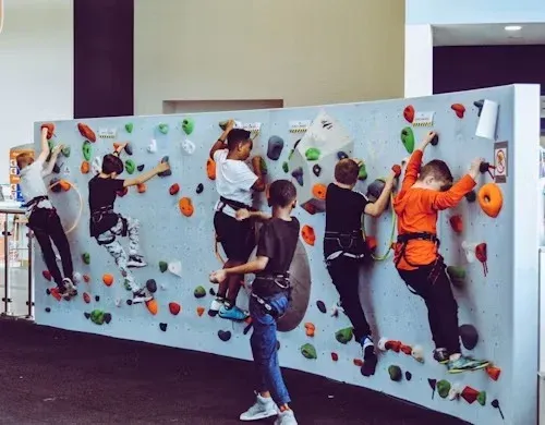 Children in harnesses climbing an indoor climbing wall