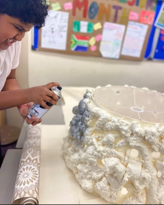 A child spraying paint onto a large foam sculpture