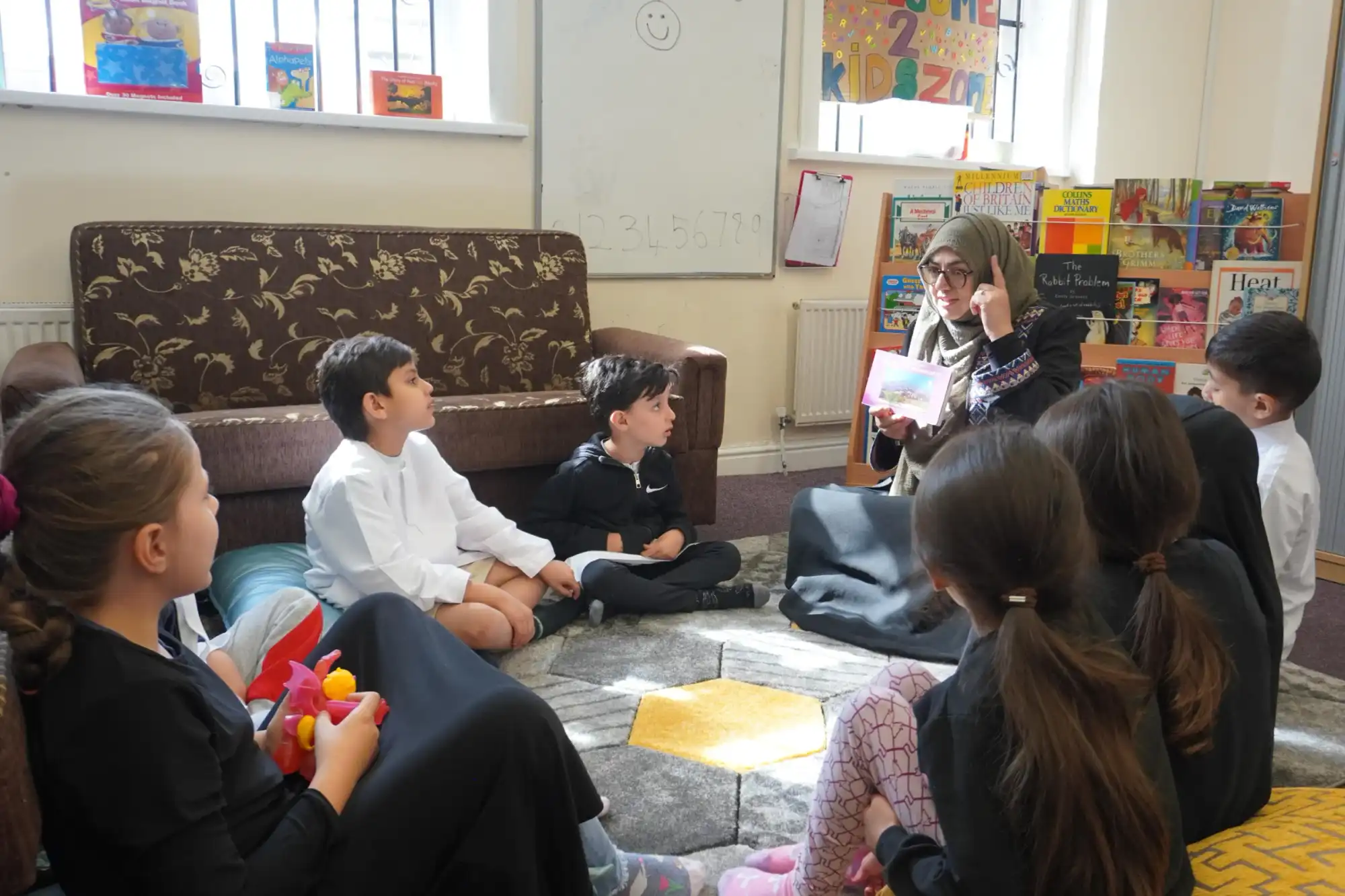 A staff member reading a story to children sitting on the carpet