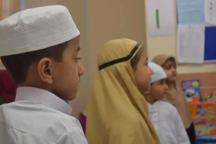 Children standing in a line at an assembly, seen from the side