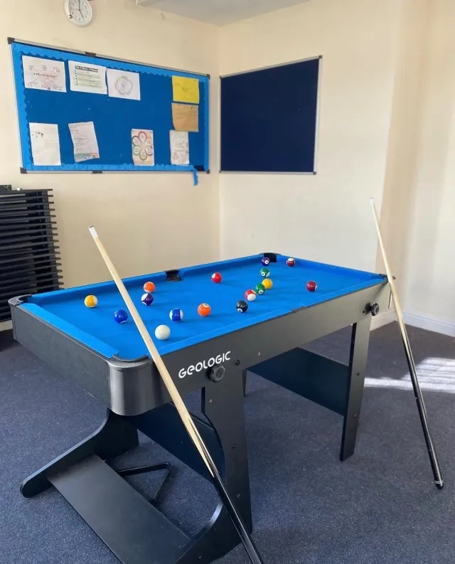 A pool table with cues and balls in the games room