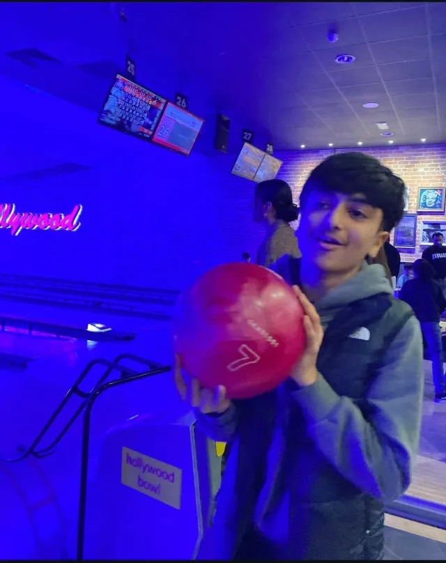 A child holding a red bowling ball at a bowling alley